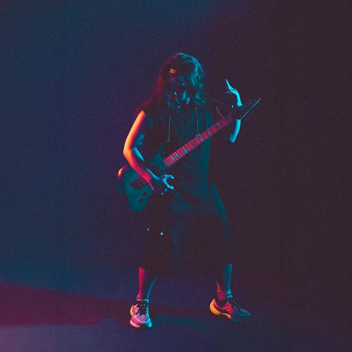 Guitarist performing energetically on stage with dark lighting.
